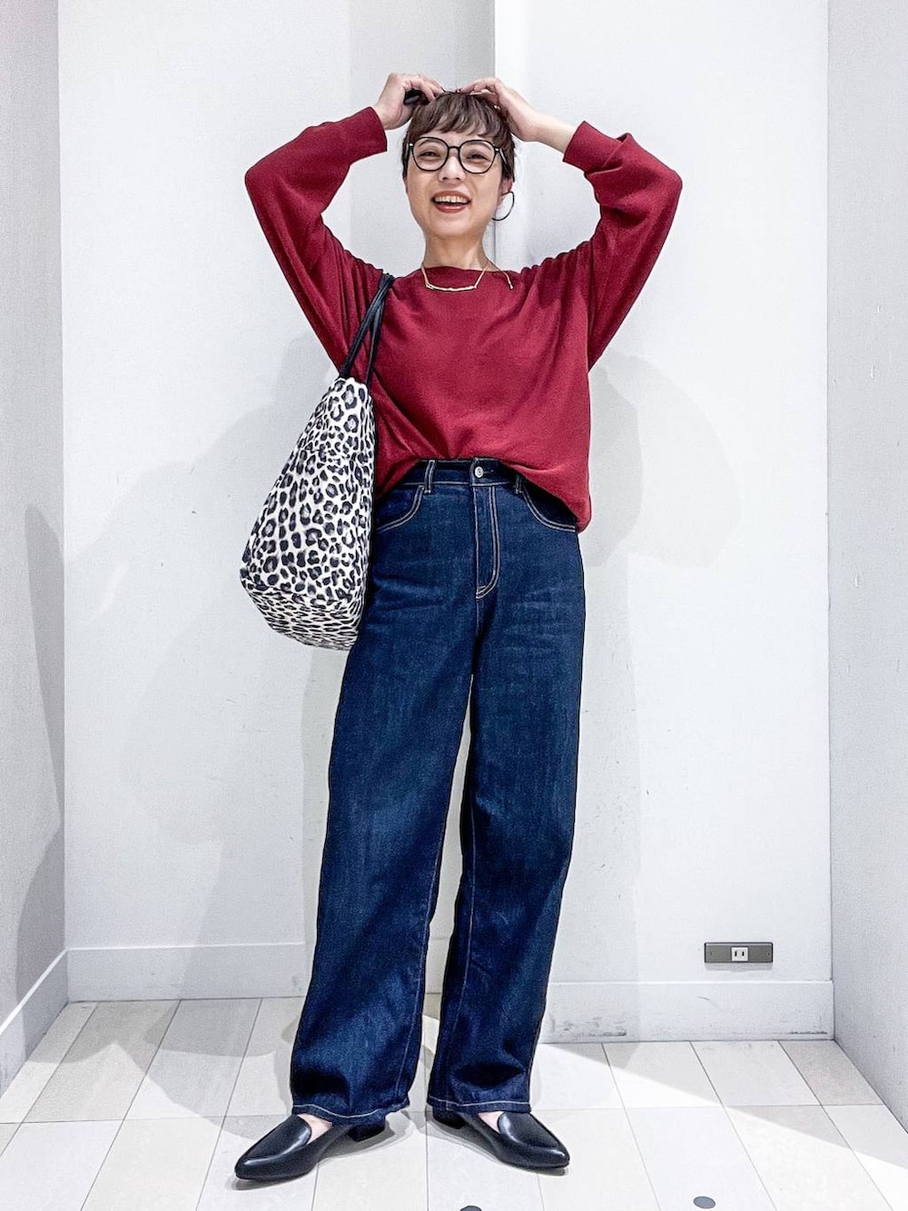 ブラック系のパンプス、レッド系のニット/セーター、ブルー系のデニムパンツを着用したレディースの秋コーディネートの6枚目の写真