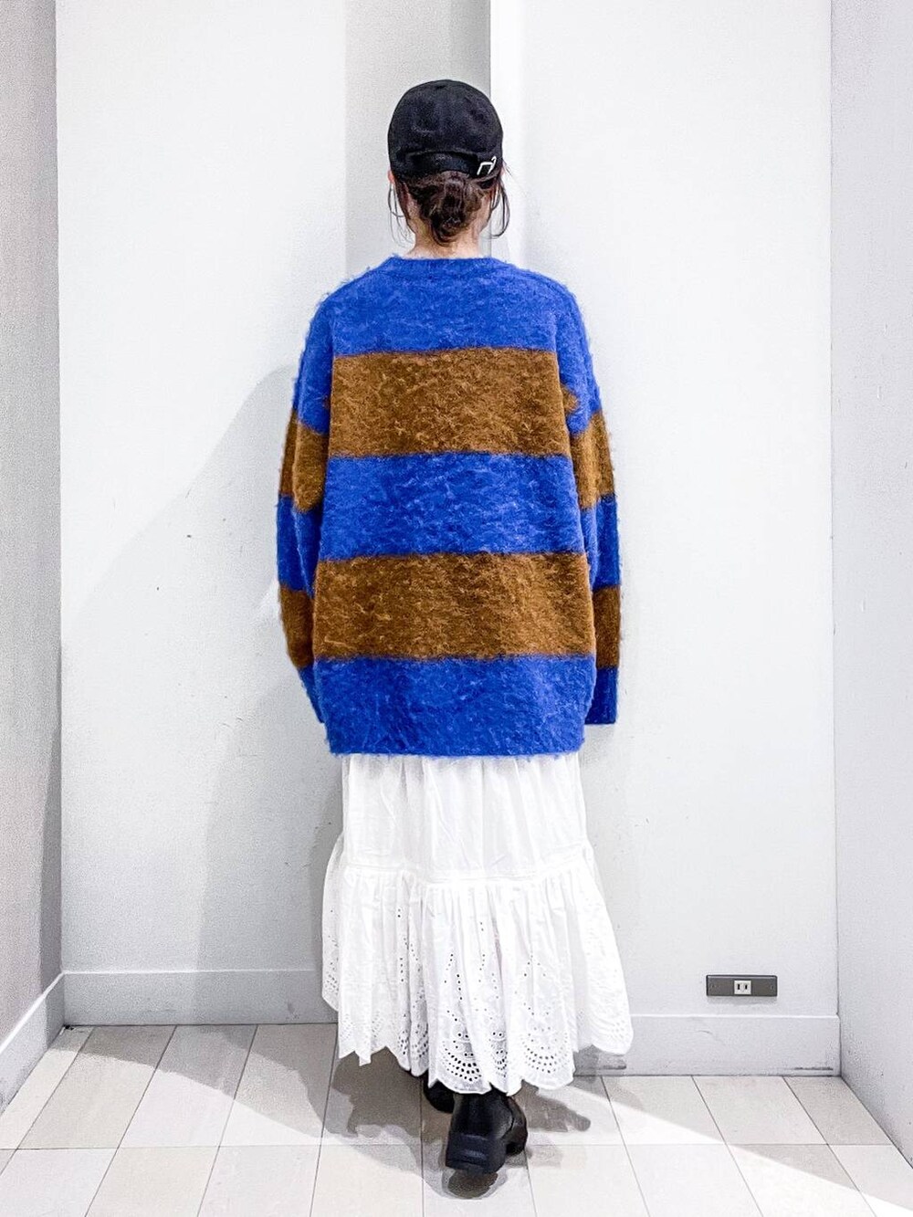 グレー系のステンカラーコート、ホワイト系のショルダーバッグ、ブルー系のニット/セーターを着用したレディースの冬コーディネートの8枚目の写真