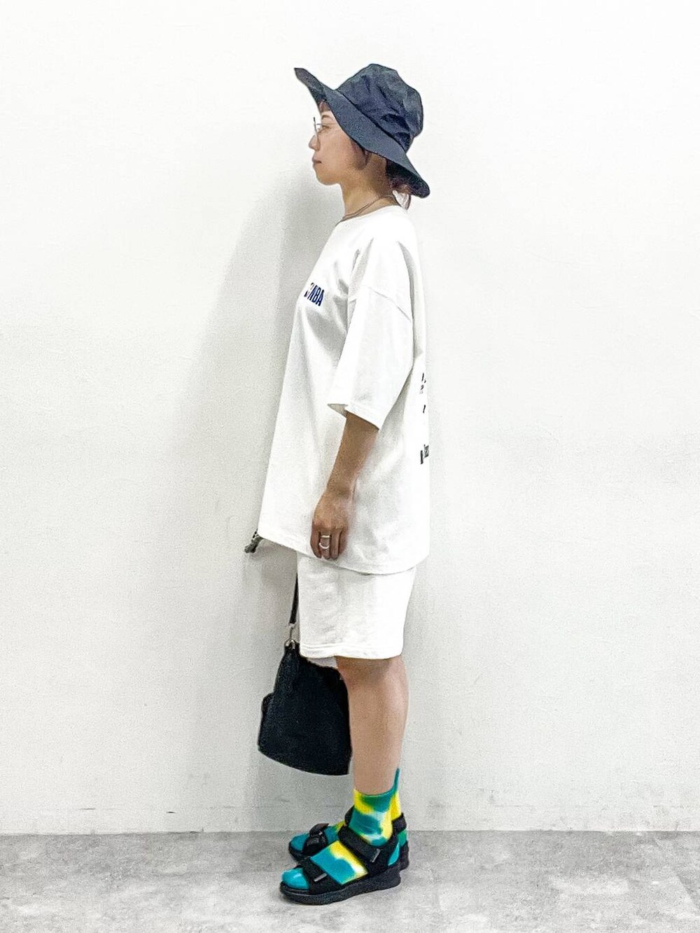 ブラック系のサンダル、ブラック系のショルダーバッグ、ホワイト系のTシャツ/カットソーを着用したレディースの夏コーディネートの4枚目の写真