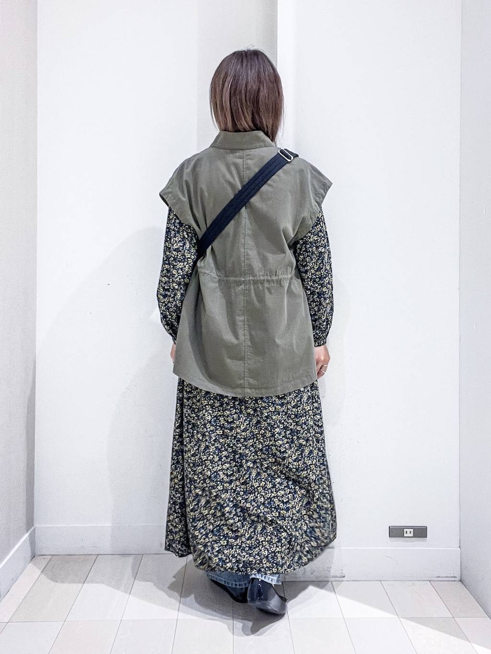 ブルー系のデニムパンツ、ブラック系のワンピース、ブラック系のバレエシューズを着用したレディースの秋コーディネートの4枚目の写真