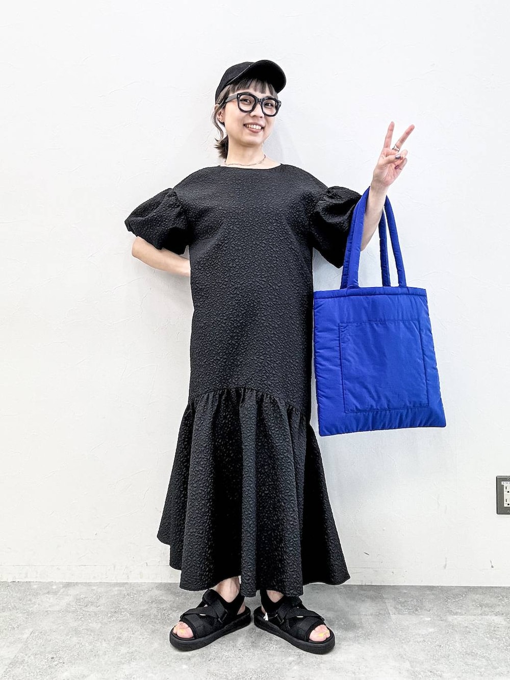 ブラック系のサンダル、ブルー系のトートバッグ、ブラック系のキャップを着用したレディースの春コーディネートの7枚目の写真