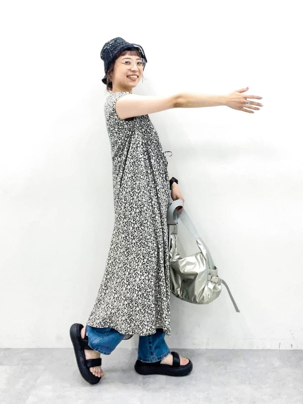 シルバー系のショルダーバッグ、ブルー系のデニムパンツ、ブラック系のサンダルを着用したレディースの夏コーディネートの5枚目の写真