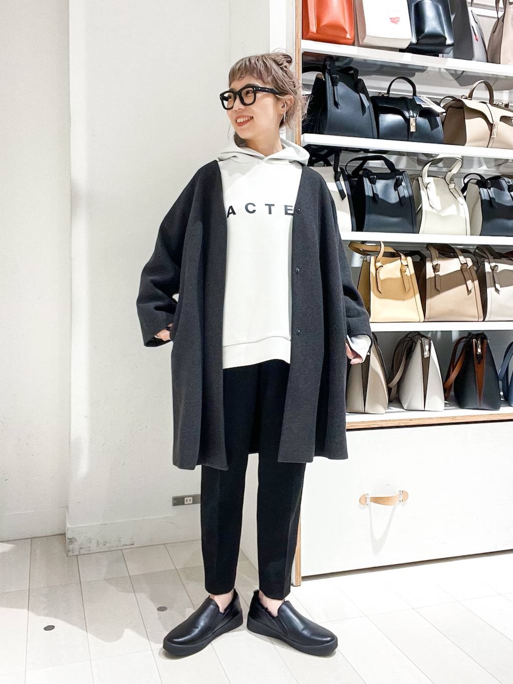 グレー系のノーカラーコート、ホワイト系のパーカー、グリーン系のショルダーバッグを着用したレディースの冬コーディネートの4枚目の写真