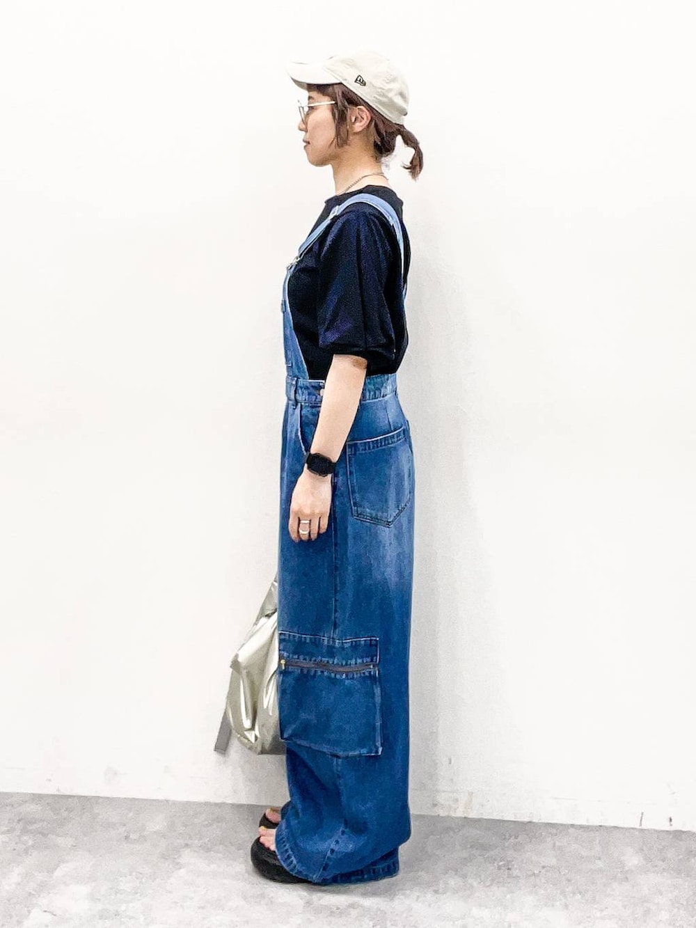 シルバー系のショルダーバッグ、ブラック系のTシャツ/カットソー、ブルー系のサロペット/オーバーオールを着用したレディースの夏コーディネートの3枚目の写真