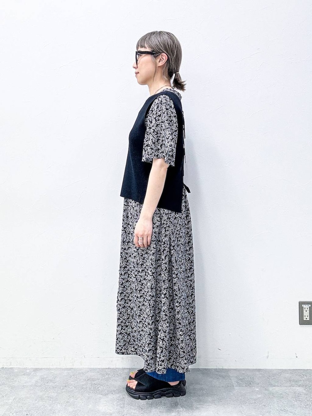 ブルー系のスラックス、ブラック系のサンダル、ブラック系のベストを着用したレディースの春コーディネートの3枚目の写真