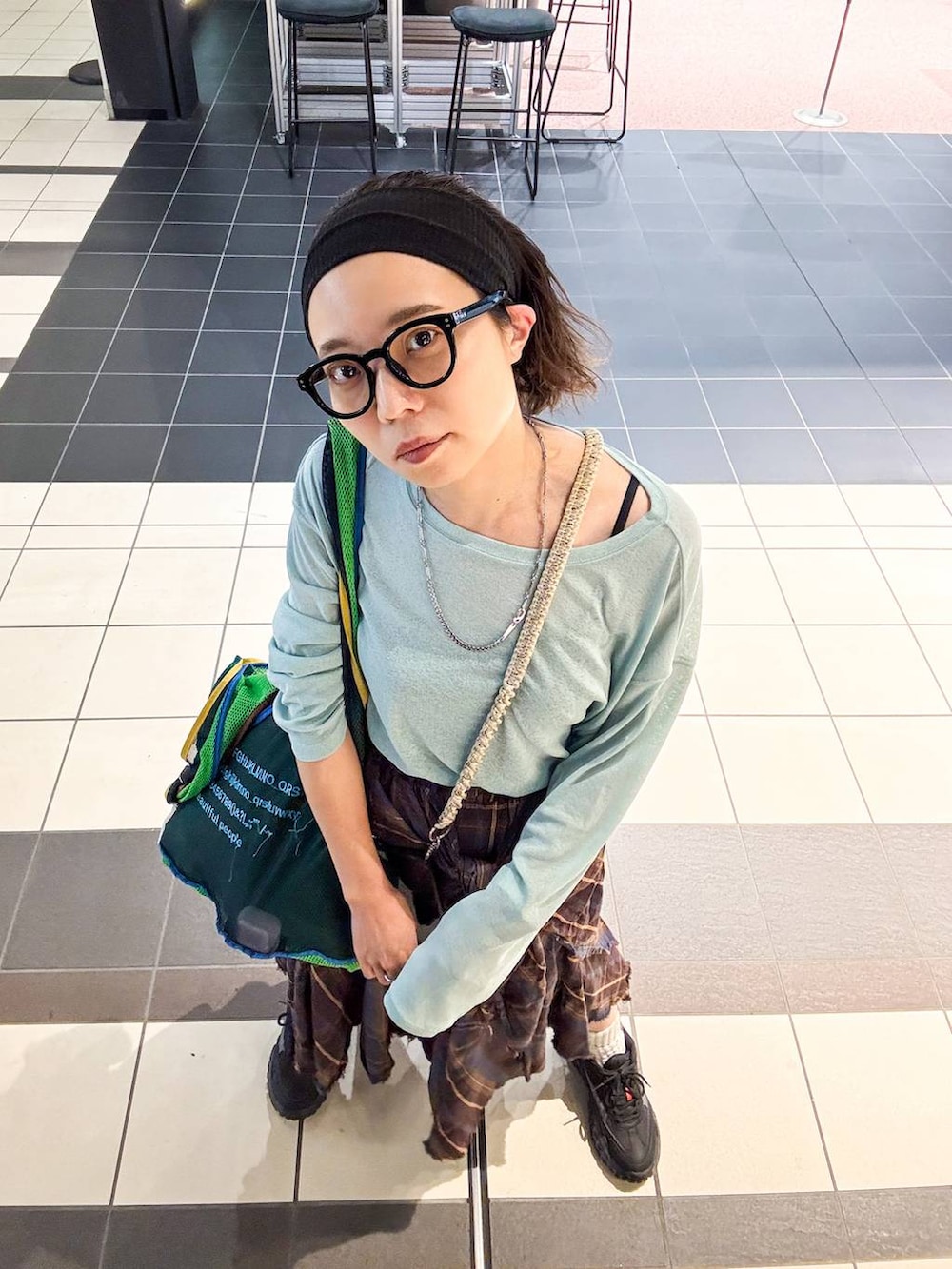 グリーン系のTシャツ/カットソー、ブラウン系のスカート、ブラック系のヘアバンドを着用したレディースの秋コーディネートの4枚目の写真