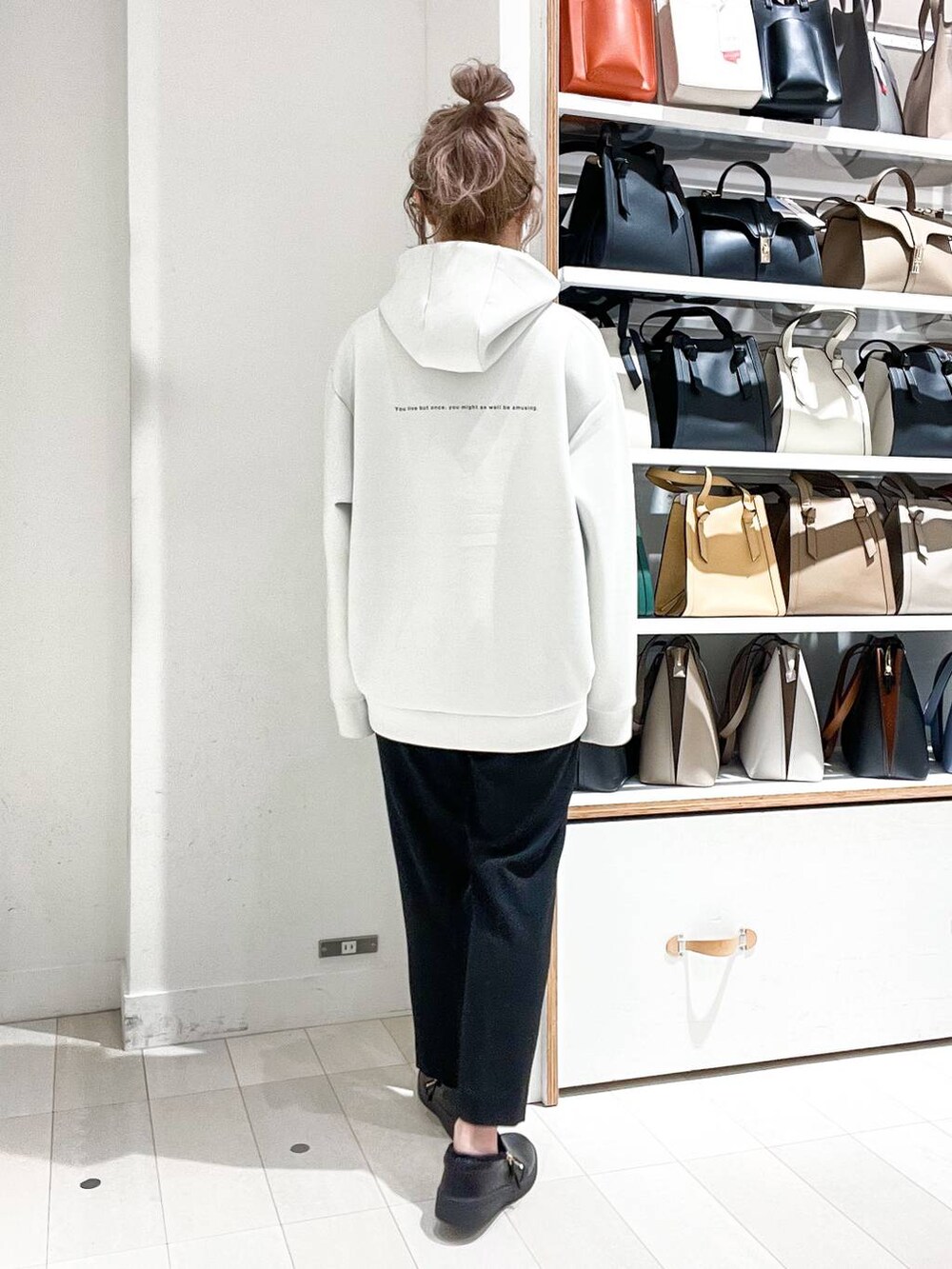 グレー系のノーカラーコート、ホワイト系のパーカー、グリーン系のショルダーバッグを着用したレディースの冬コーディネートの9枚目の写真