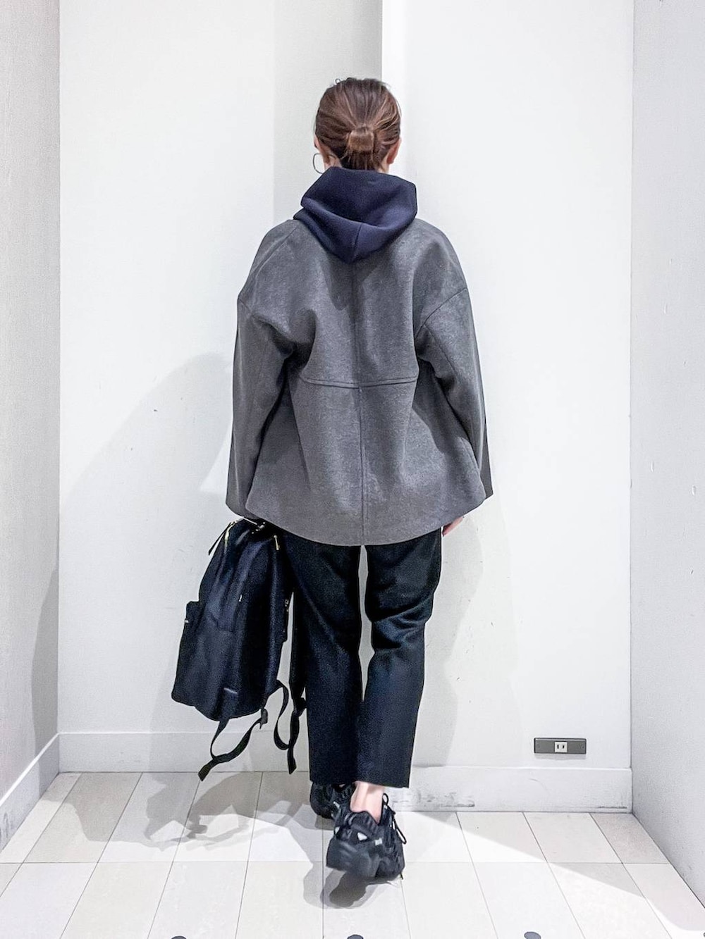 ブラック系のバックパック/リュック、グレー系のノーカラーコート、ブラック系のその他パンツを着用したレディースの秋コーディネートの4枚目の写真