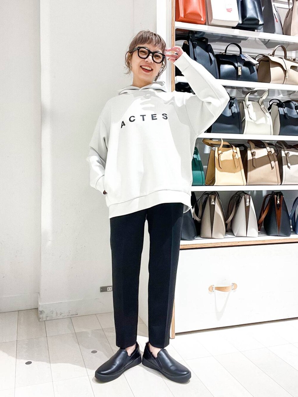 グレー系のノーカラーコート、ホワイト系のパーカー、グリーン系のショルダーバッグを着用したレディースの冬コーディネートの7枚目の写真