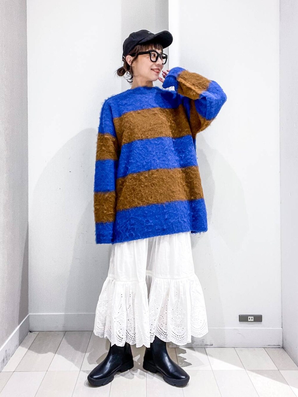 グレー系のステンカラーコート、ホワイト系のショルダーバッグ、ブルー系のニット/セーターを着用したレディースの冬コーディネートの6枚目の写真