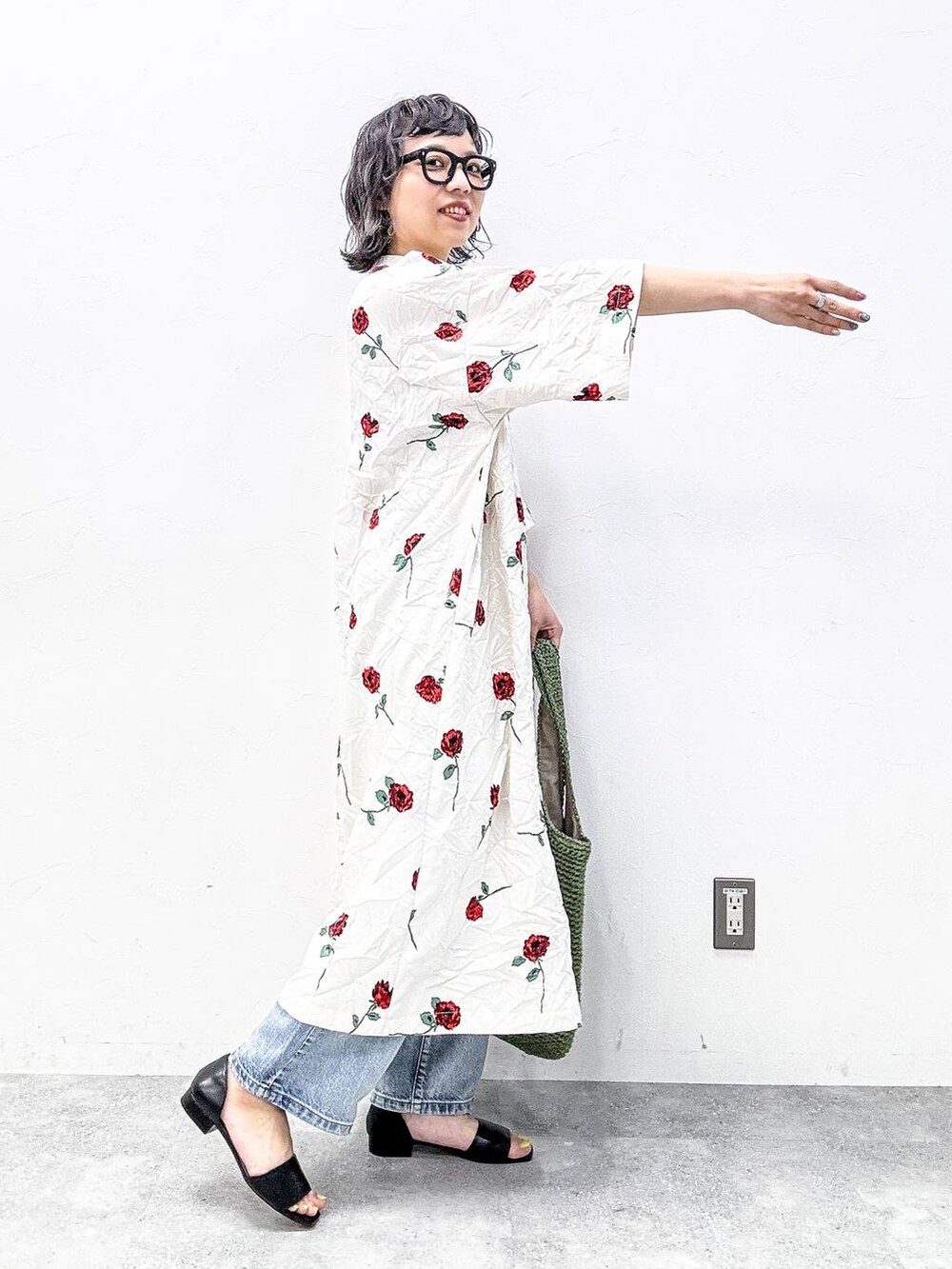 グリーン系のショルダーバッグ、ブラック系のサンダル、ブルー系のデニムパンツを着用したレディースの春コーディネートの5枚目の写真