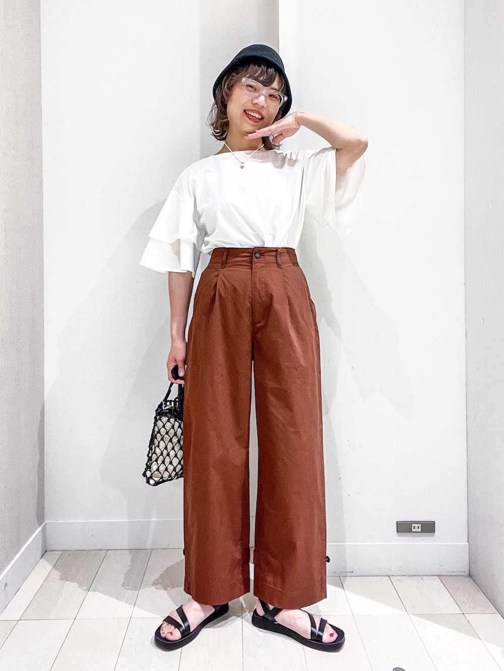 ホワイト系のTシャツ/カットソー、ブラウン系のその他パンツ、ブラック系のバッグを着用したレディースの夏コーディネートの2枚目の写真
