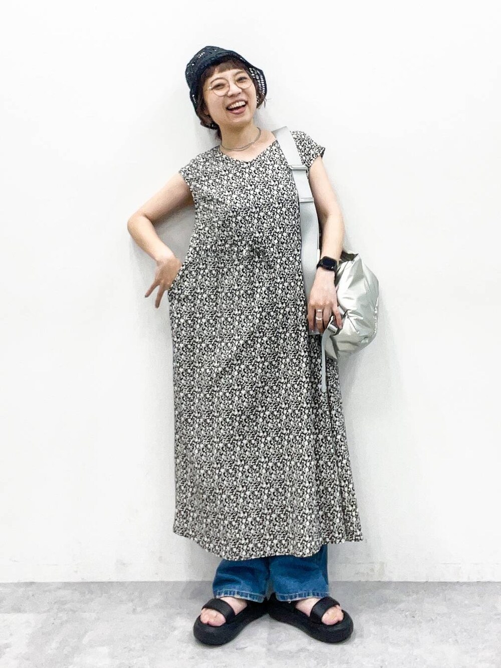 シルバー系のショルダーバッグ、ブルー系のデニムパンツ、ブラック系のサンダルを着用したレディースの夏コーディネートの2枚目の写真