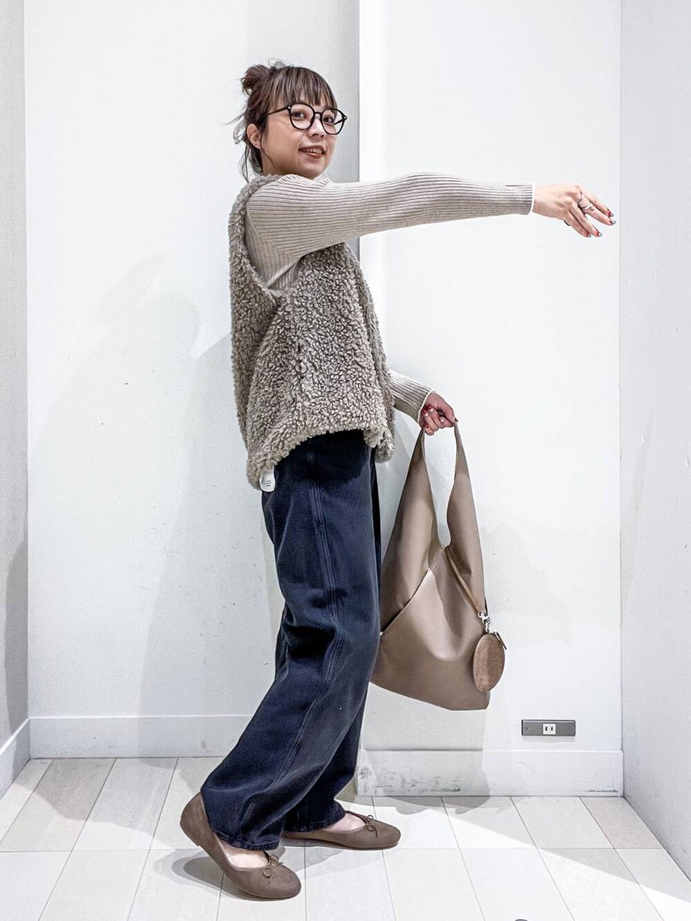 ベージュ系のニット/セーター、ブラック系のデニムパンツ、ベージュ系のトートバッグを着用したレディースの秋コーディネートの5枚目の写真