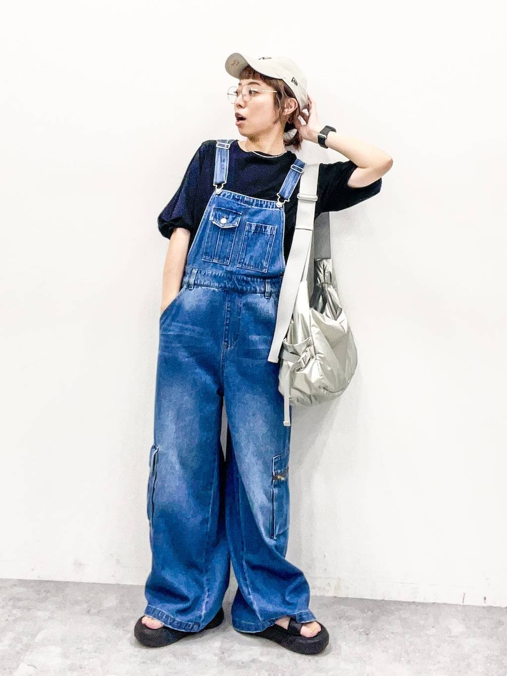 シルバー系のショルダーバッグ、ブラック系のTシャツ/カットソー、ブルー系のサロペット/オーバーオールを着用したレディースの夏コーディネートの7枚目の写真