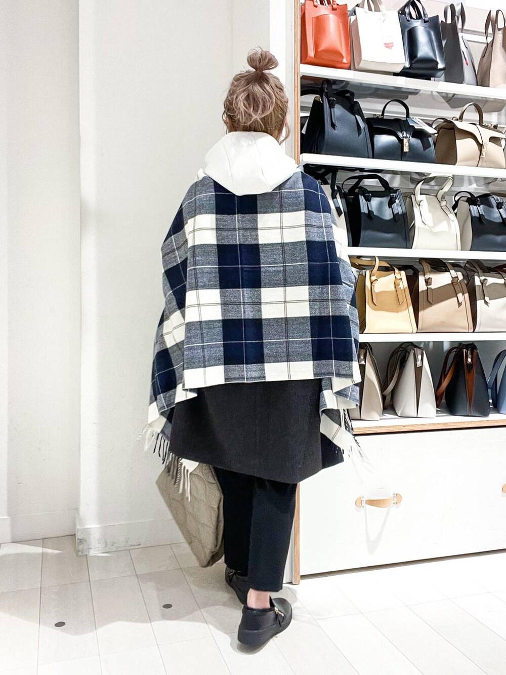 グレー系のノーカラーコート、ホワイト系のパーカー、グリーン系のショルダーバッグを着用したレディースの冬コーディネートの3枚目の写真