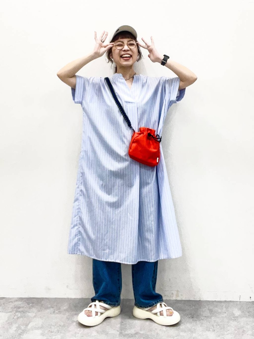 ホワイト系のサンダル、オレンジ系のショルダーバッグ、ブルー系のデニムパンツを着用したレディースの夏コーディネートの2枚目の写真