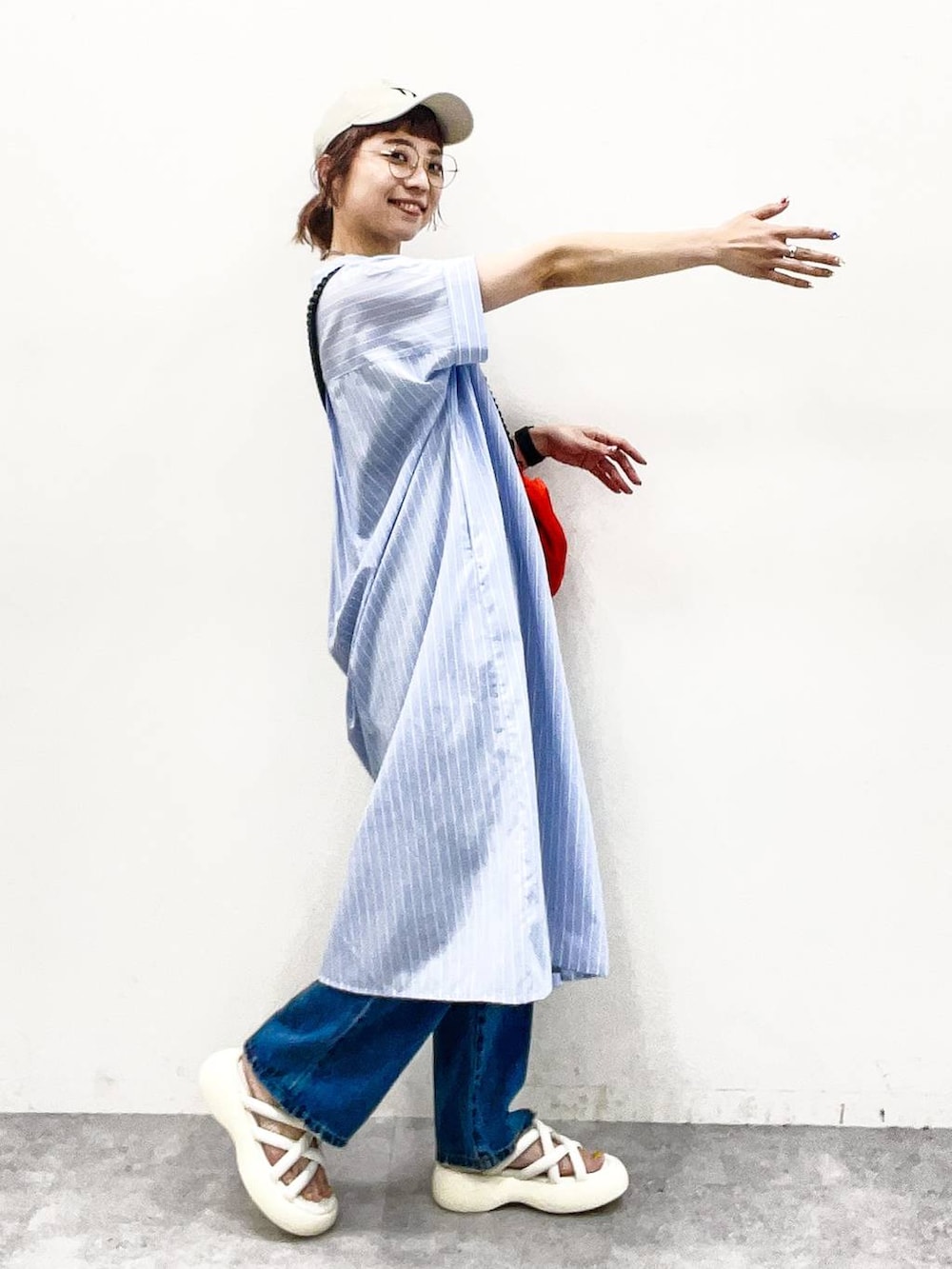 ホワイト系のサンダル、オレンジ系のショルダーバッグ、ブルー系のデニムパンツを着用したレディースの夏コーディネートの5枚目の写真