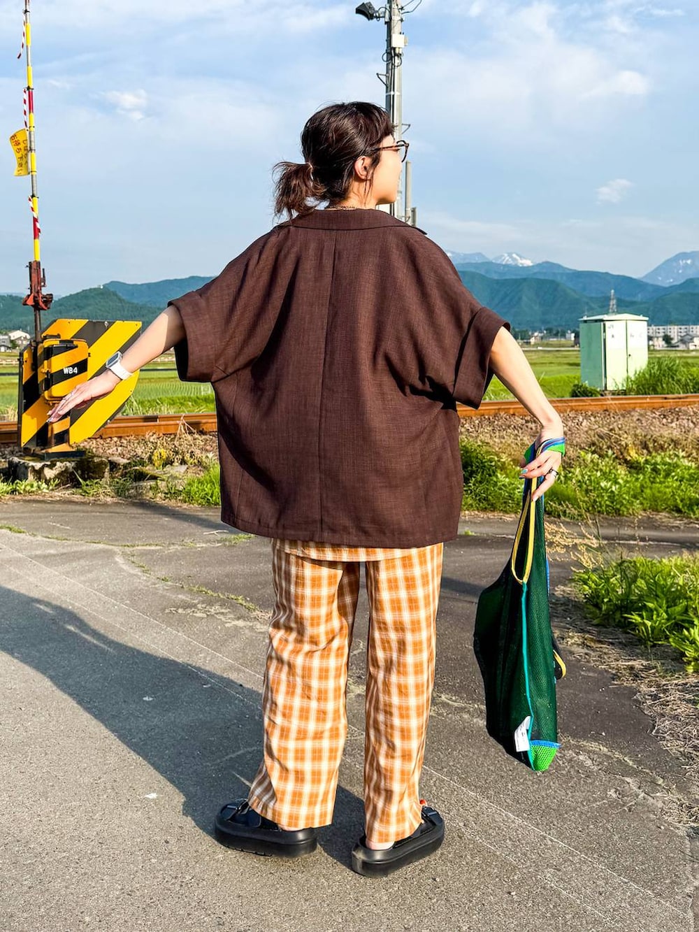 ホワイト系のタンクトップ、ブラック系のサンダル、ブラウン系のテーラードジャケットを着用したレディースの夏コーディネートの5枚目の写真