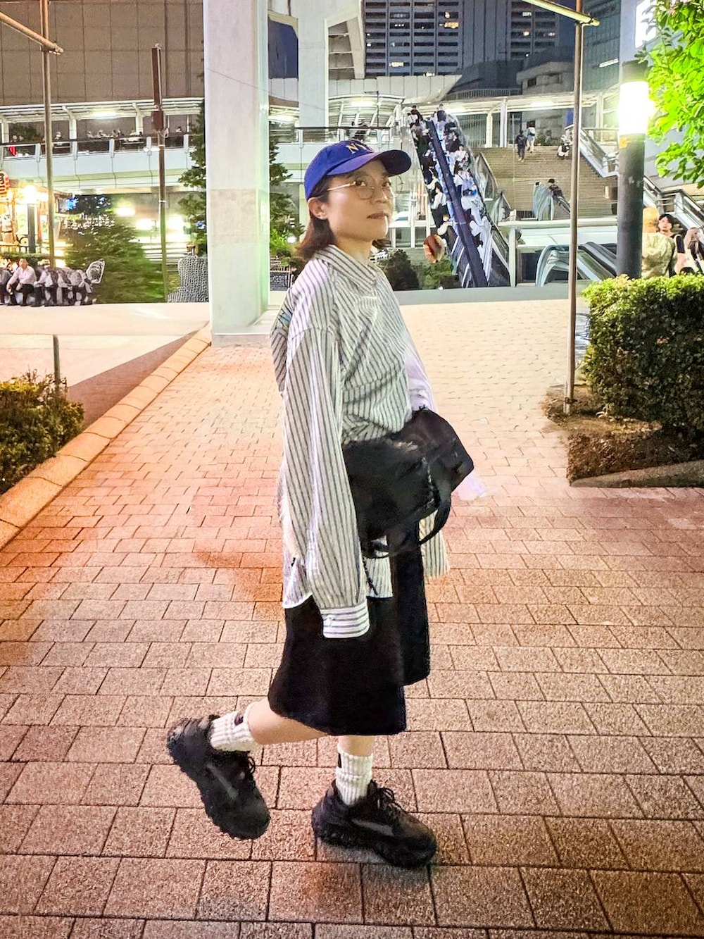 ブラック系のデニムパンツ、ベージュ系のシャツ/ブラウス、ブルー系のキャップを着用したレディースの秋コーディネートの5枚目の写真