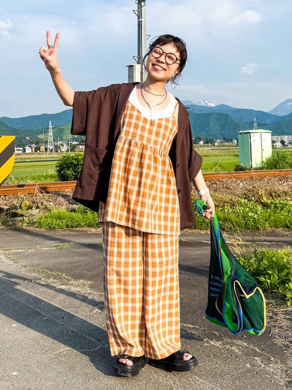 ホワイト系のタンクトップ、ブラック系のサンダル、ブラウン系のテーラードジャケットを着用したレディースの夏コーディネートの3枚目の写真