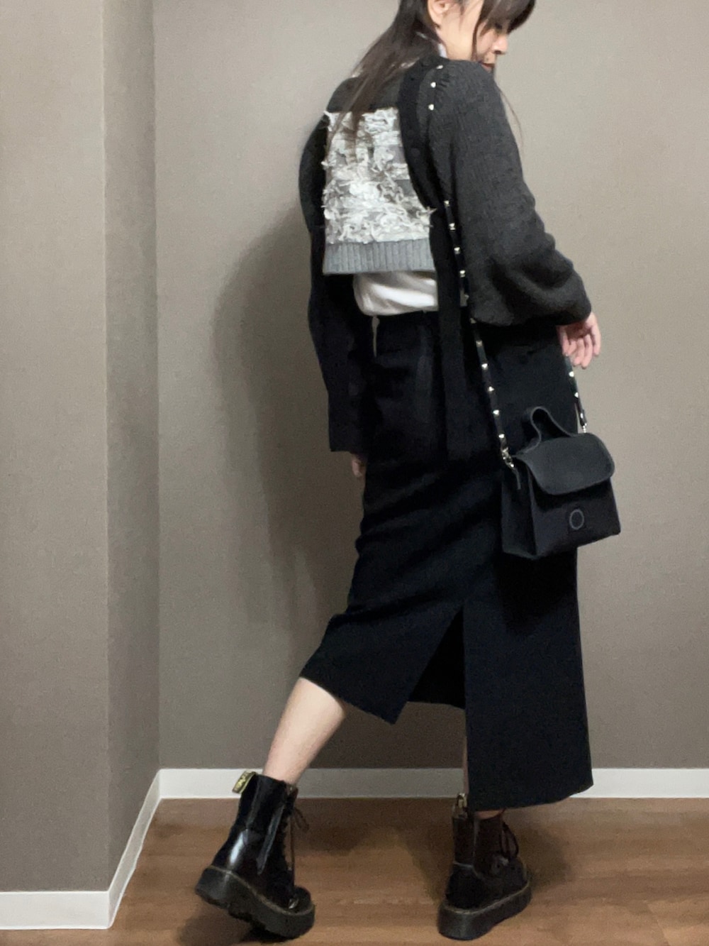 ブラック系のショルダーバッグ、ブラック系のスカート、グレー系のニット/セーターを着用したレディースの冬コーディネートの2枚目の写真