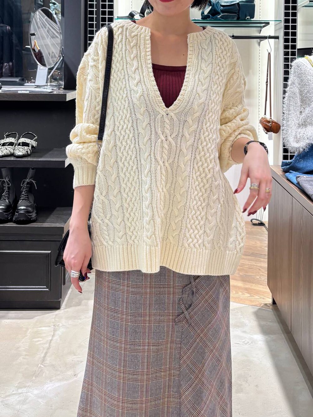 レッド系のタンクトップ、ブラック系のハンドバッグ、ホワイト系のニット/セーターを着用したレディースの秋コーディネートの2枚目の写真