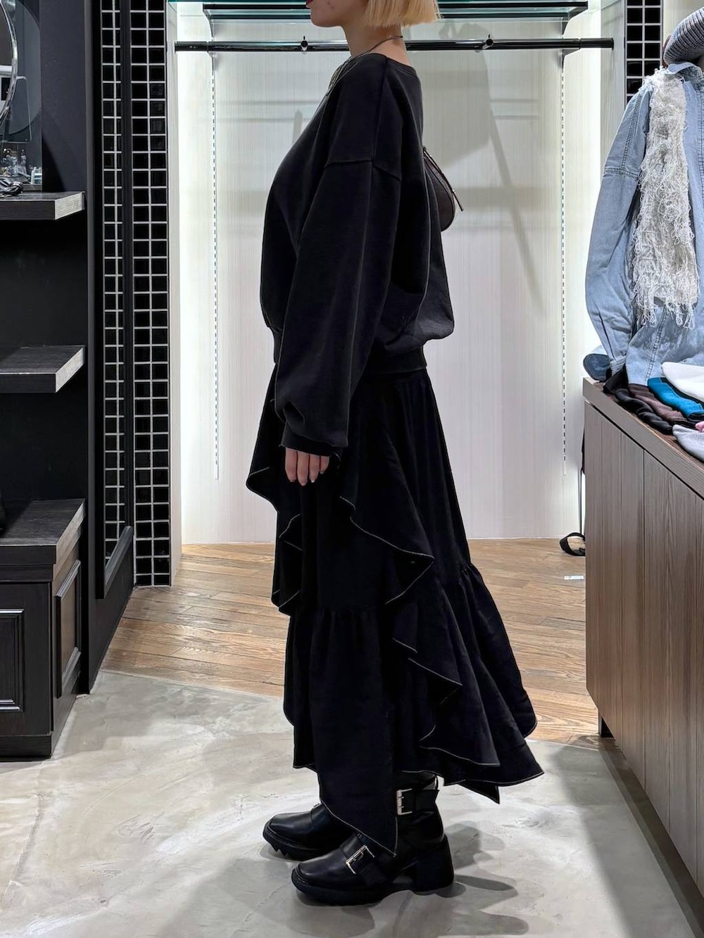 ブラック系のブーツ、ブラック系のスカート、ブラウン系のハンドバッグを着用したレディースの春コーディネートの5枚目の写真