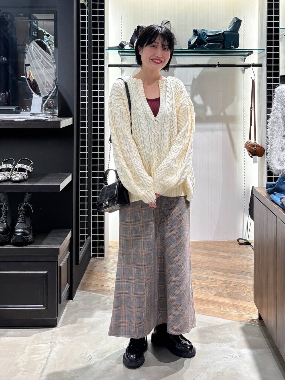 レッド系のタンクトップ、ブラック系のハンドバッグ、ホワイト系のニット/セーターを着用したレディースの秋コーディネートの8枚目の写真