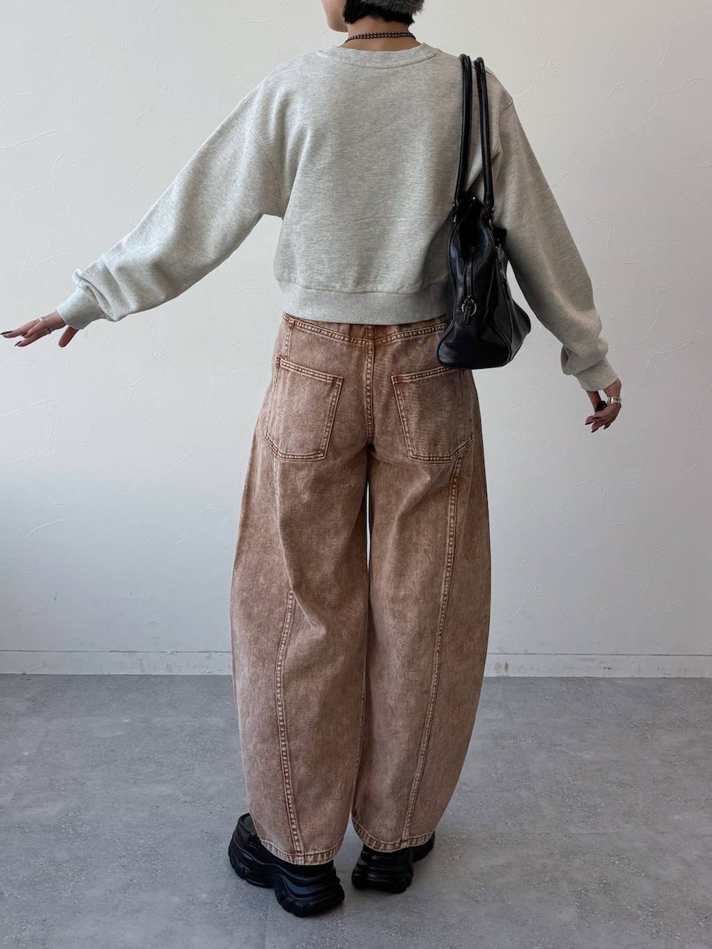 ブラック系のボストンバッグ、ブラック系のローファー、ブラウン系のデニムパンツを着用したレディースの冬コーディネートの2枚目の写真