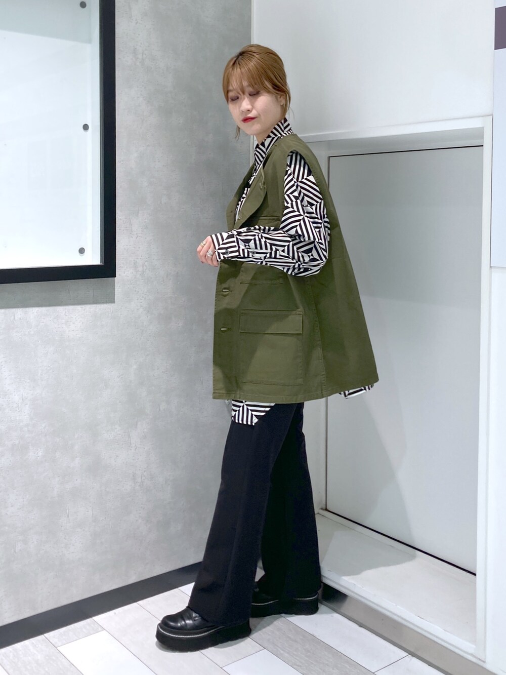 ホワイト系のシャツ/ブラウス、グリーン系のベスト、ブラック系のスラックスを着用したレディースの秋コーディネートの4枚目の写真