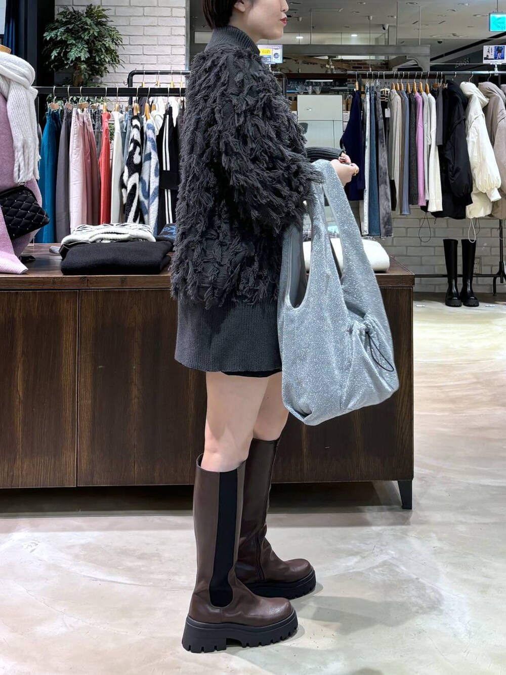 ブラウン系のブーツ、グレー系のトートバッグ、グレー系のニット/セーターを着用したレディースの冬コーディネートの3枚目の写真