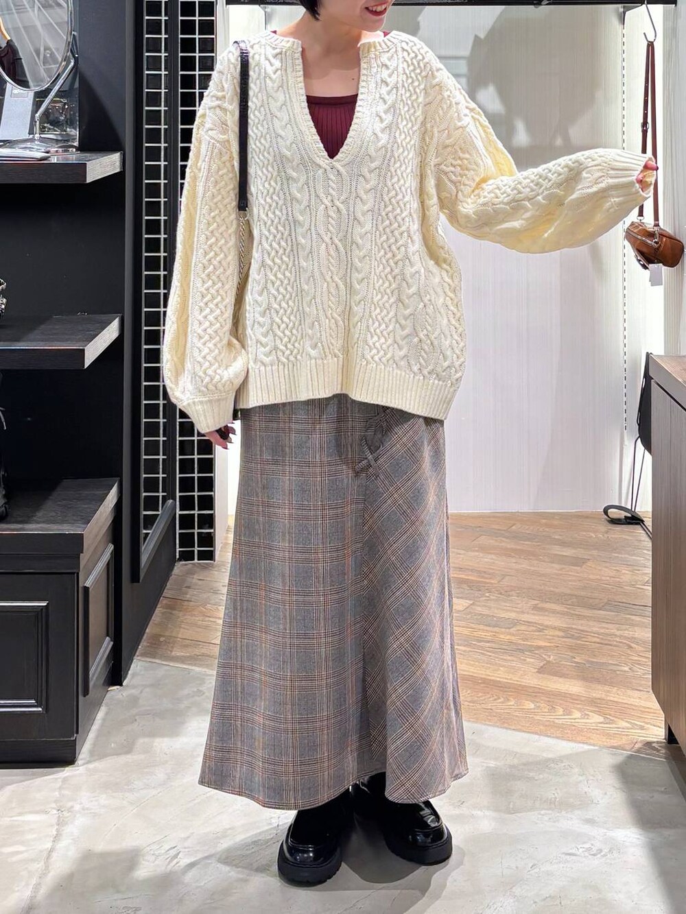 レッド系のタンクトップ、ブラック系のハンドバッグ、ホワイト系のニット/セーターを着用したレディースの秋コーディネートの6枚目の写真