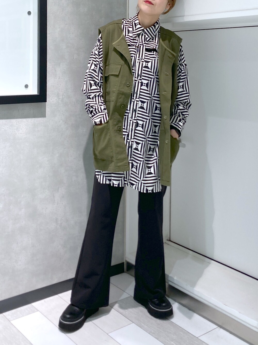 ホワイト系のシャツ/ブラウス、グリーン系のベスト、ブラック系のスラックスを着用したレディースの秋コーディネートの2枚目の写真