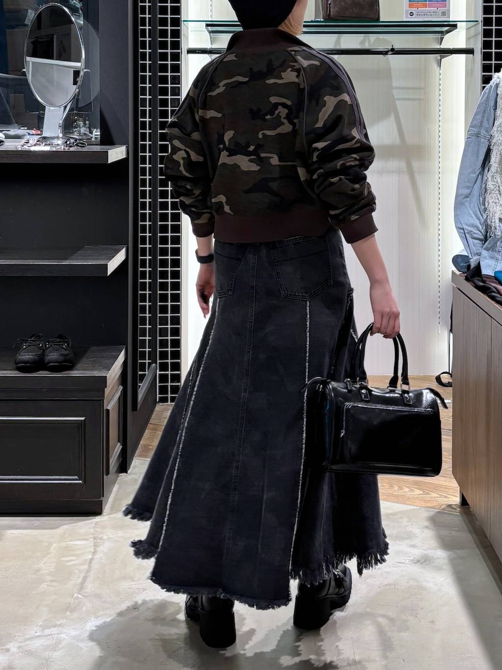 ブラック系のブーツ、ブラック系のショルダーバッグ、ブラック系のデニムスカートを着用したレディースの春コーディネートの2枚目の写真