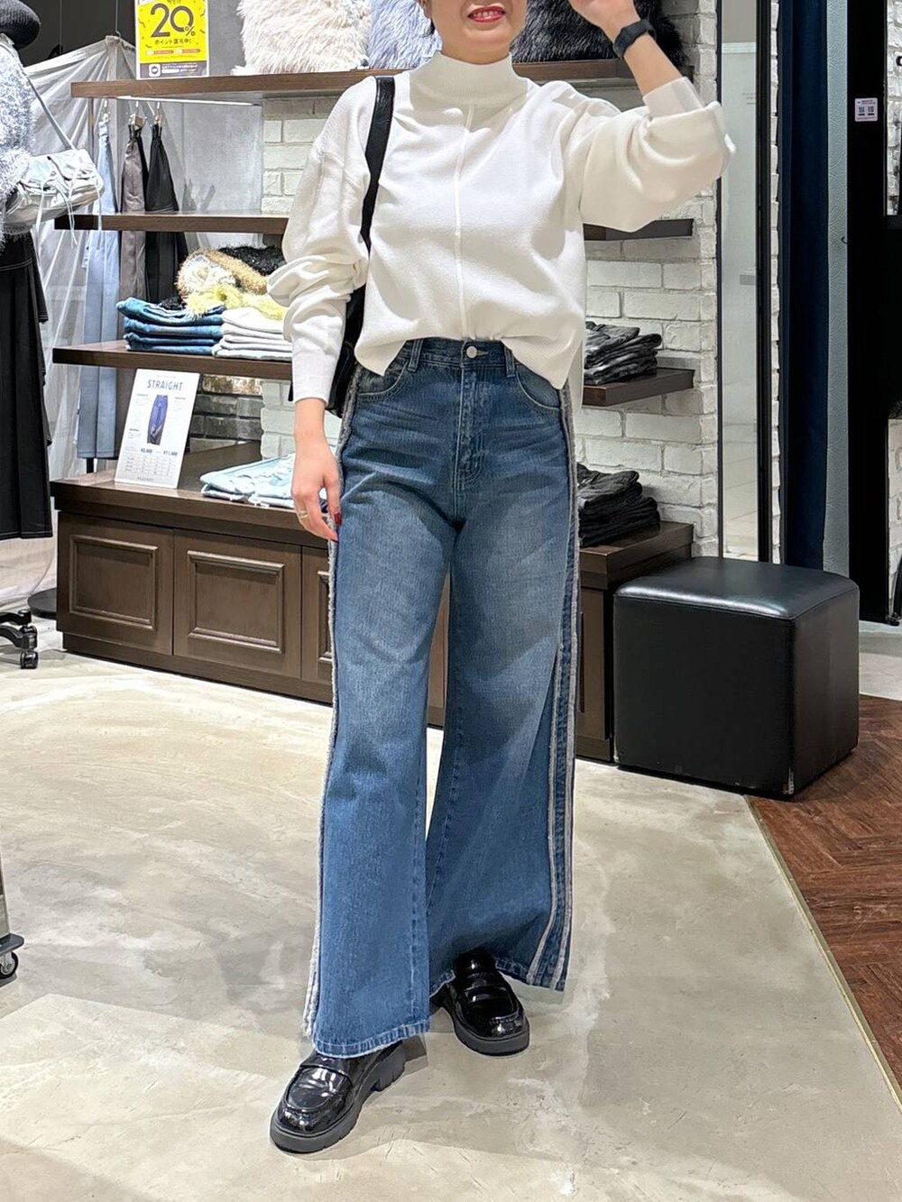 ホワイト系のニット/セーター、ブラック系のショルダーバッグ、ブルー系のデニムパンツを着用したレディースの冬コーディネートの5枚目の写真