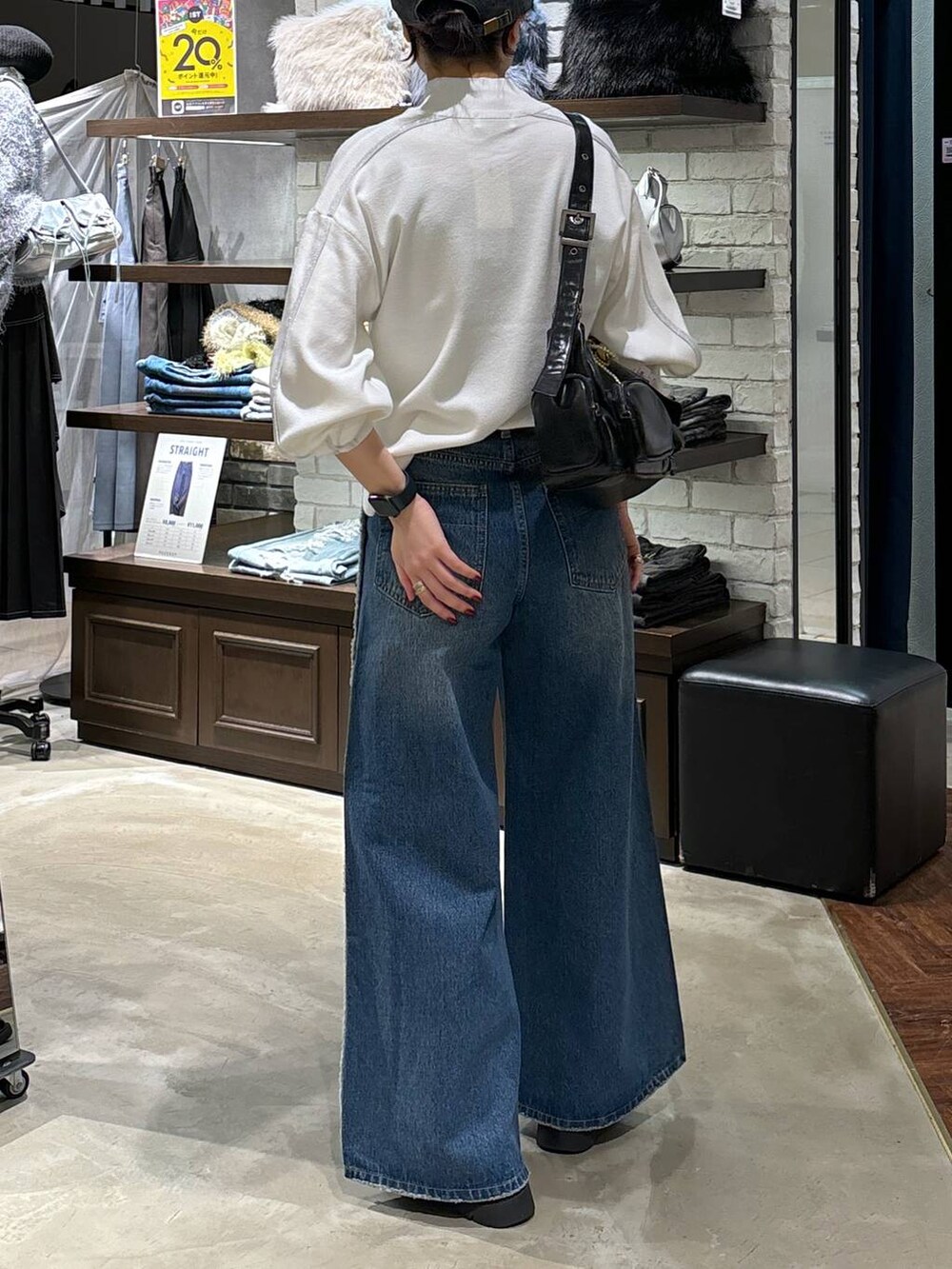 ホワイト系のニット/セーター、ブラック系のショルダーバッグ、ブルー系のデニムパンツを着用したレディースの冬コーディネートの3枚目の写真