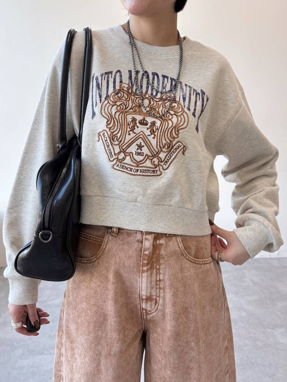 ブラック系のボストンバッグ、ブラック系のローファー、ブラウン系のデニムパンツを着用したレディースの冬コーディネートの4枚目の写真