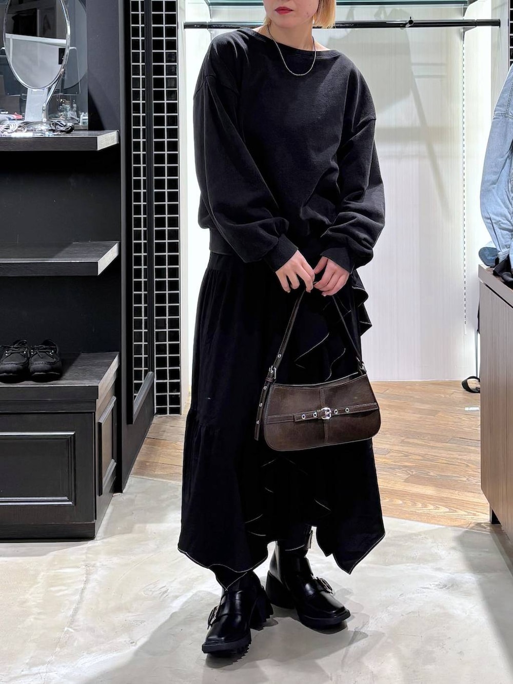 ブラック系のブーツ、ブラック系のスカート、ブラウン系のハンドバッグを着用したレディースの春コーディネートの6枚目の写真