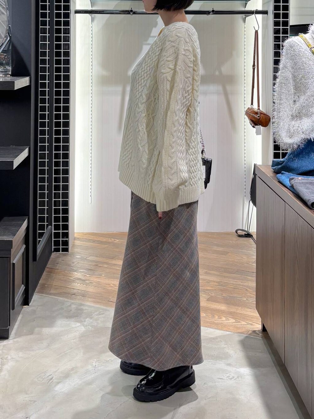 レッド系のタンクトップ、ブラック系のハンドバッグ、ホワイト系のニット/セーターを着用したレディースの秋コーディネートの7枚目の写真