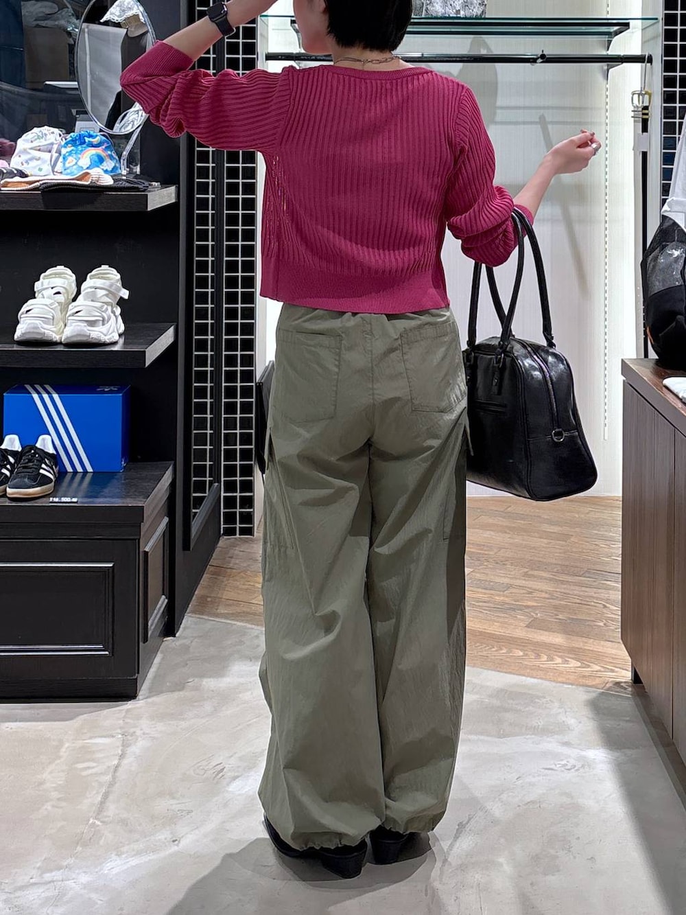 ブラック系のボストンバッグ、ブラック系のパンプス、グリーン系のカーゴパンツを着用したレディースの春コーディネートの2枚目の写真