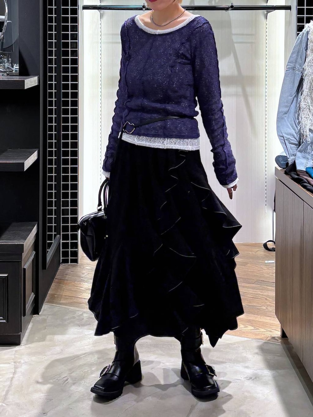 ブラック系のブーツ、ブラック系のスカート、ブラック系のショルダーバッグを着用したレディースの春コーディネートの6枚目の写真