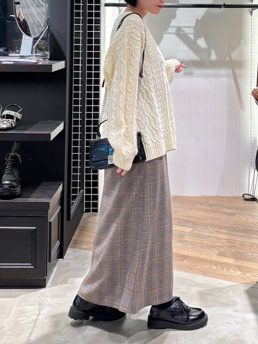 レッド系のタンクトップ、ブラック系のハンドバッグ、ホワイト系のニット/セーターを着用したレディースの秋コーディネートの5枚目の写真