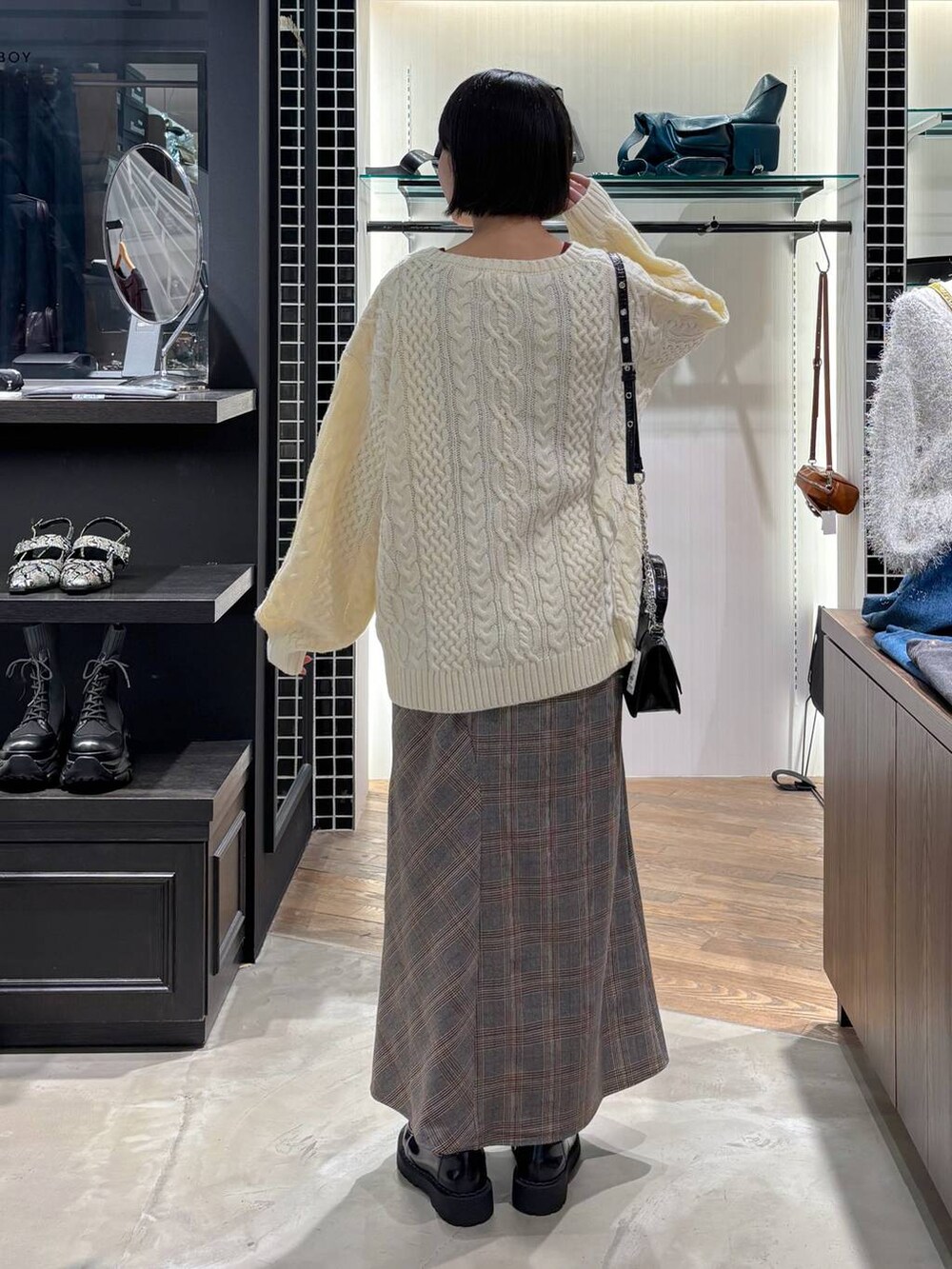 レッド系のタンクトップ、ブラック系のハンドバッグ、ホワイト系のニット/セーターを着用したレディースの秋コーディネートの4枚目の写真