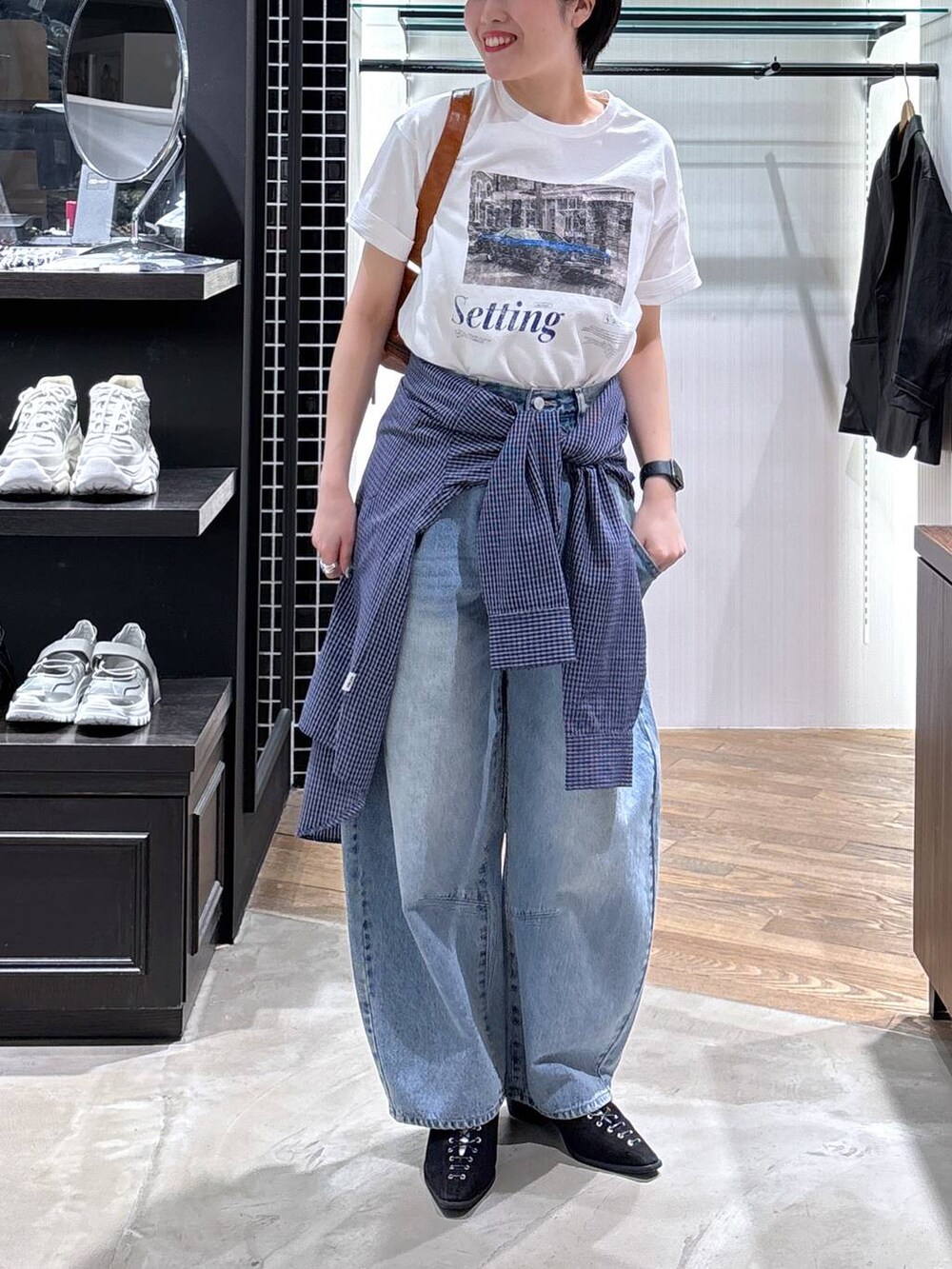 ブラック系のパンプス、ブラウン系のショルダーバッグ、ブルー系のデニムパンツを着用したレディースの春コーディネートの5枚目の写真