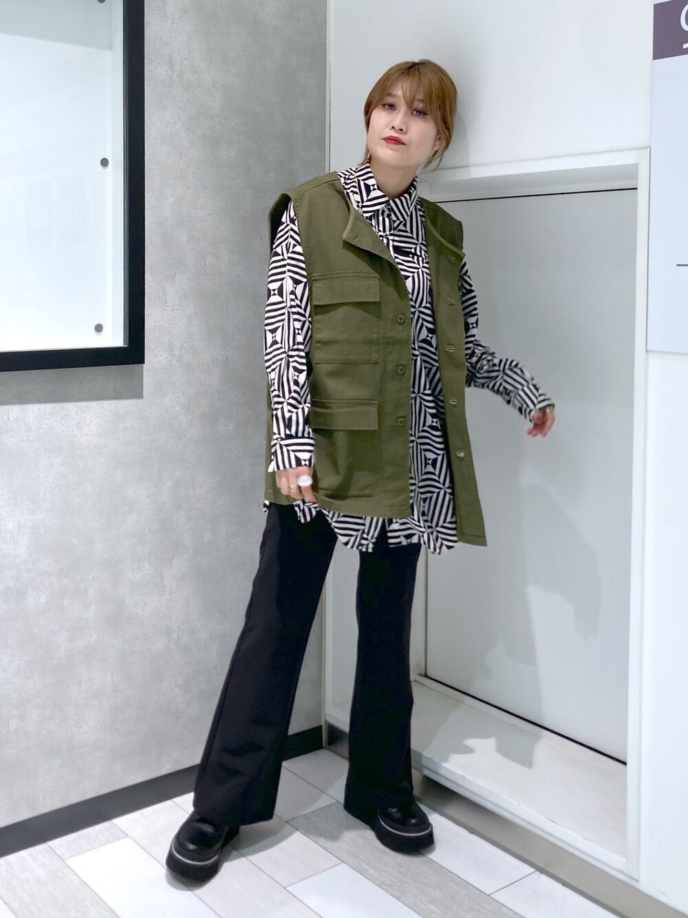 ホワイト系のシャツ/ブラウス、グリーン系のベスト、ブラック系のスラックスを着用したレディースの秋コーディネートの5枚目の写真