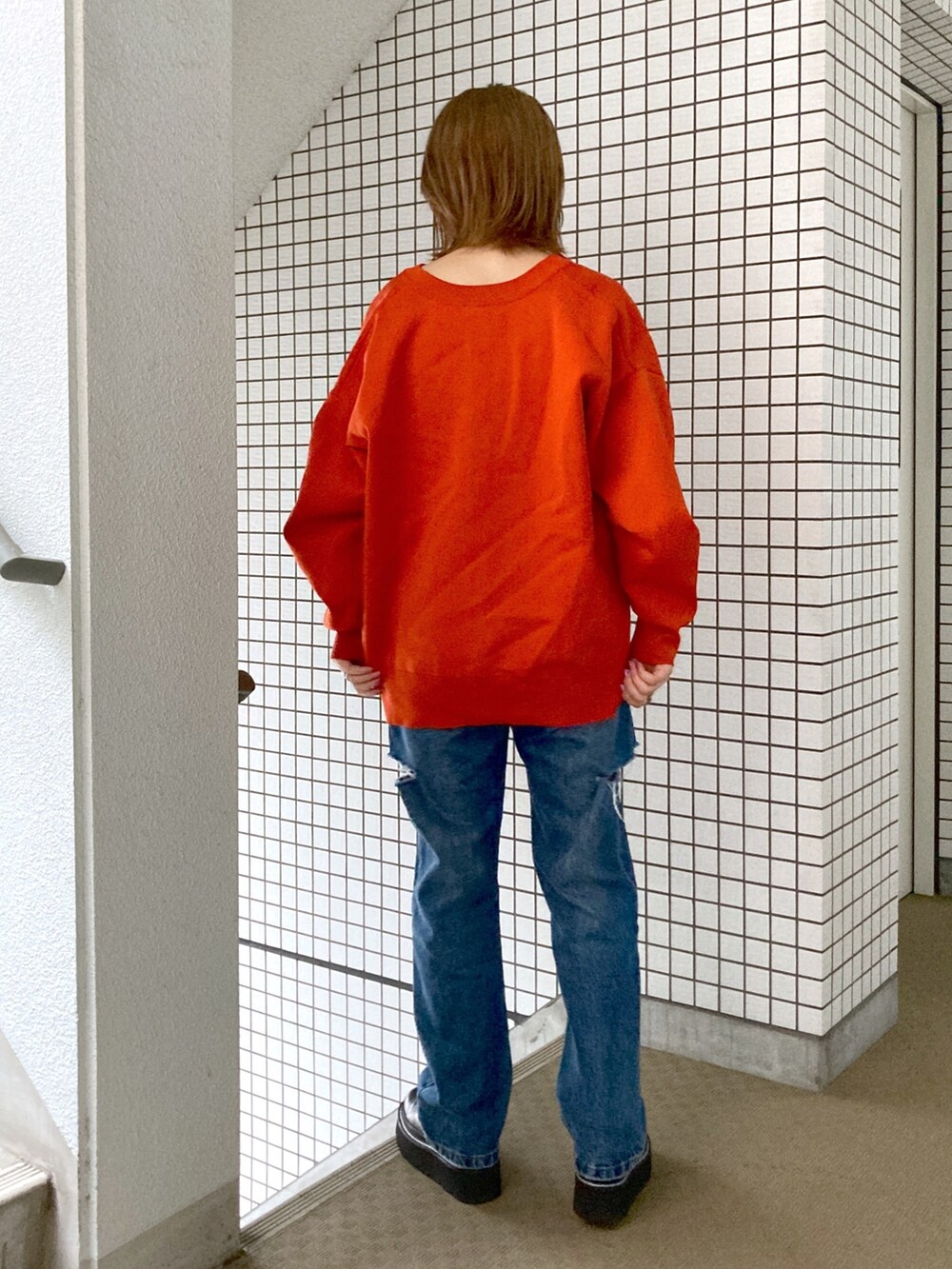 グレー系のタンクトップ、オレンジ系のカーディガン/ボレロ、ブルー系のデニムパンツを着用したレディースの秋コーディネートの4枚目の写真