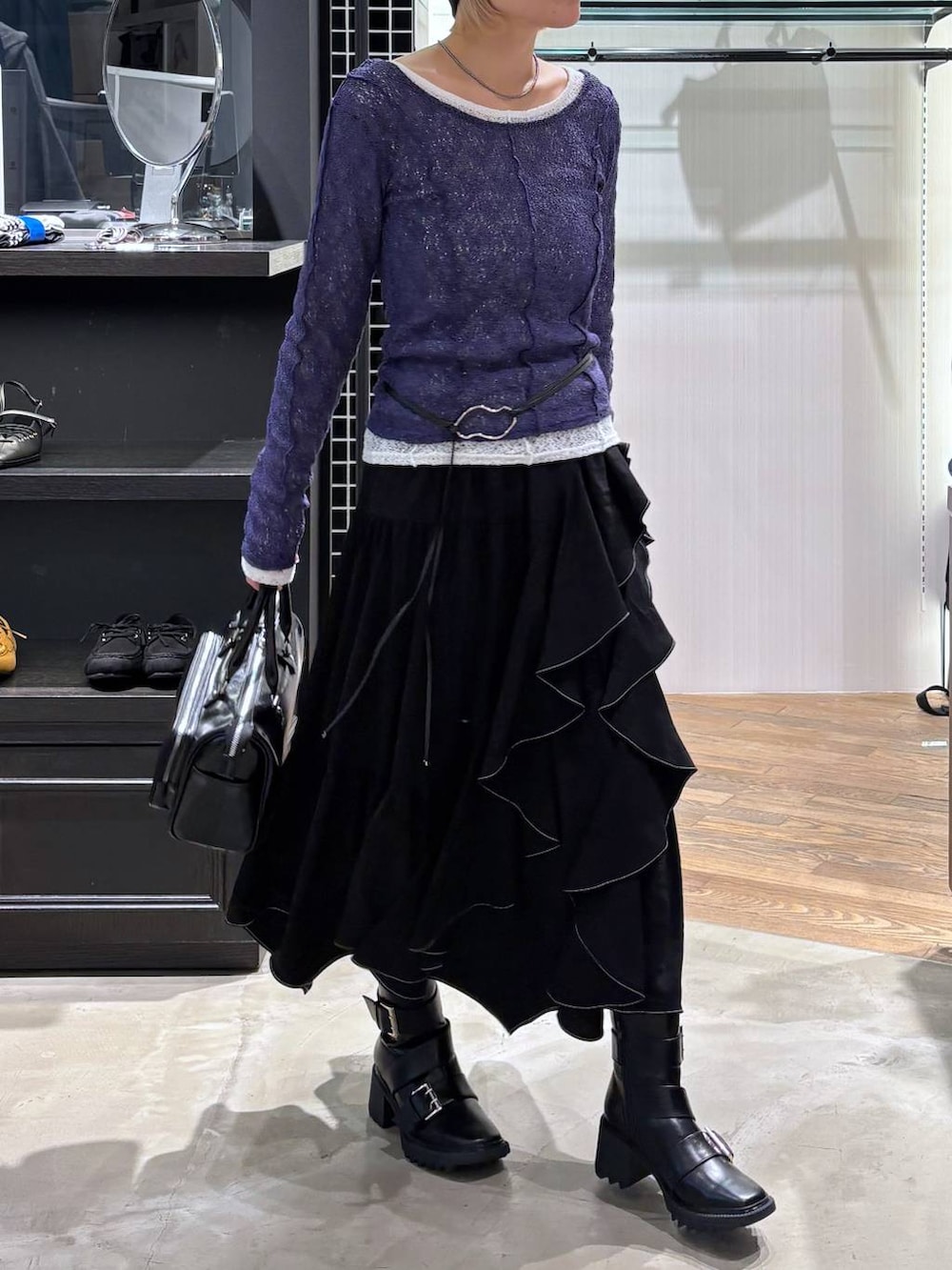 ブラック系のブーツ、ブラック系のスカート、ブラック系のショルダーバッグを着用したレディースの春コーディネートの3枚目の写真