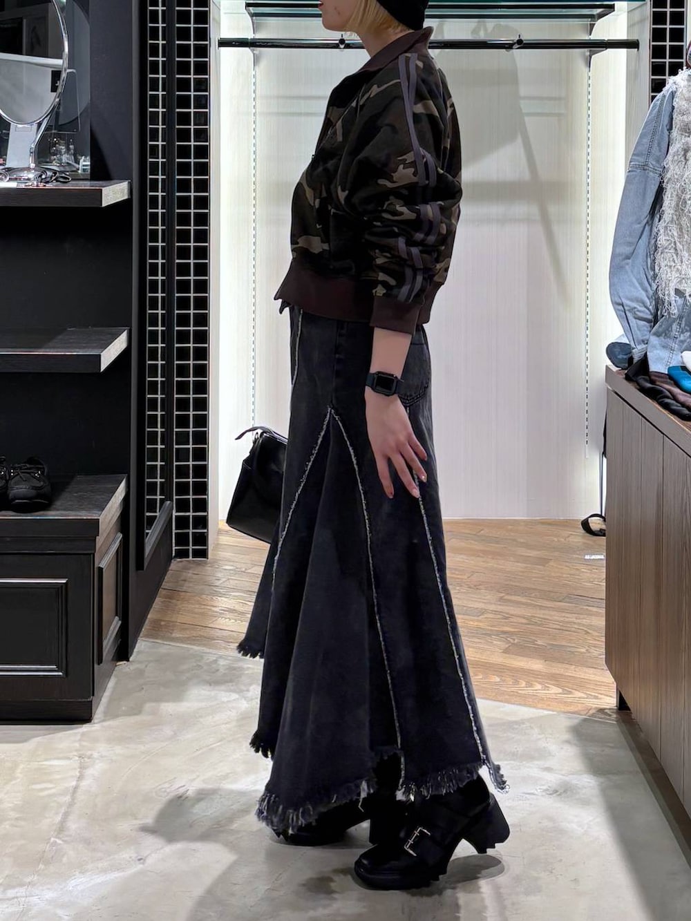 ブラック系のブーツ、ブラック系のショルダーバッグ、ブラック系のデニムスカートを着用したレディースの春コーディネートの4枚目の写真