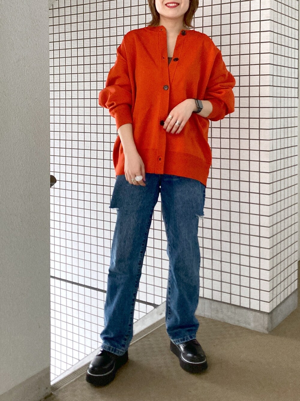 グレー系のタンクトップ、オレンジ系のカーディガン/ボレロ、ブルー系のデニムパンツを着用したレディースの秋コーディネートの5枚目の写真